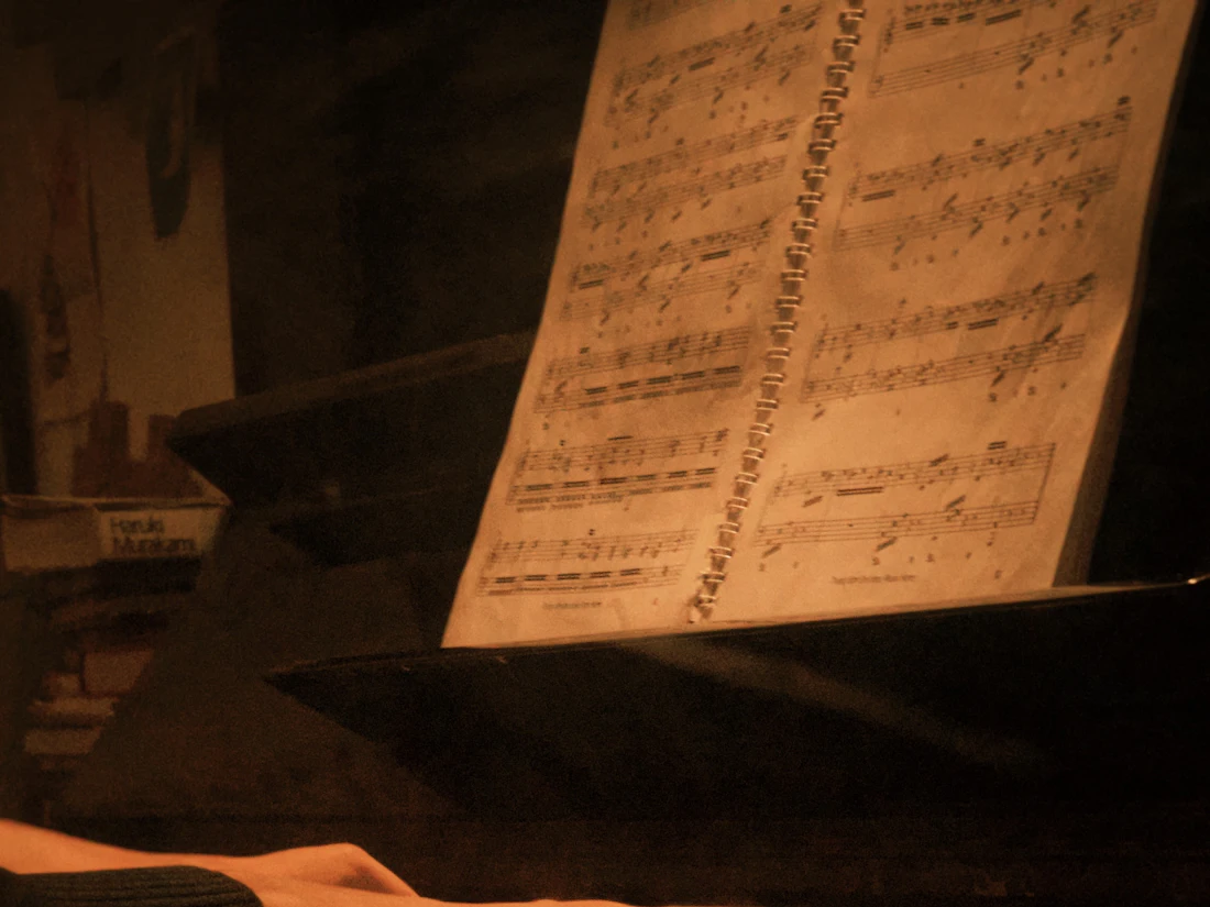Hands playing piano keys with sheet music